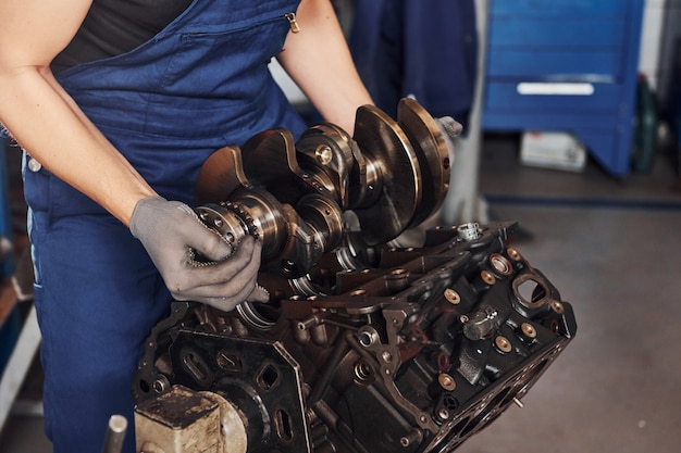 Professional repairman in garage works with broken automobile engine