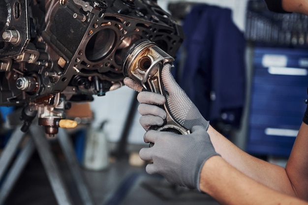 Professional repairman works with broken automobile engine