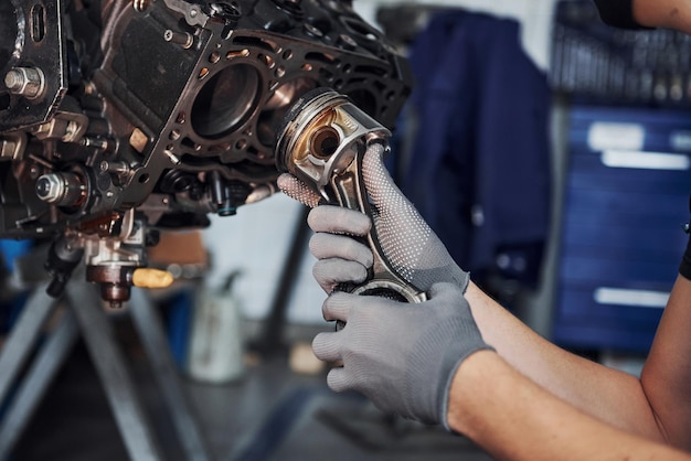 Professional repairman works with broken automobile engine