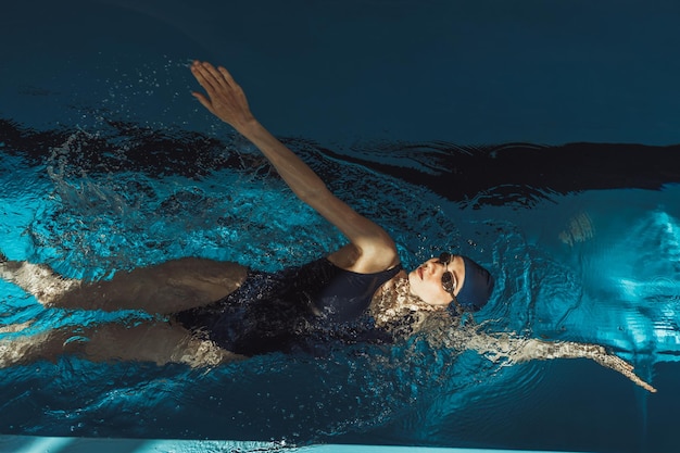 professional swimmer in swimsuit goggles and cap doing backstroke while swimming during training