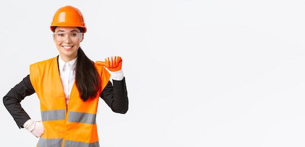 Professional and talented confident smiling asian female engineer construction architect in safety helmet and glasses pointing at herself proud promote own abilities and skills white background