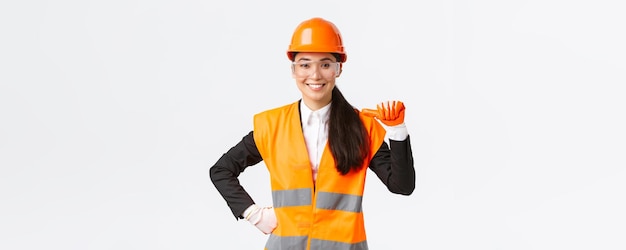 Professional and talented confident smiling asian female engineer construction architect in safety helmet and glasses pointing at herself proud promote own abilities and skills white background