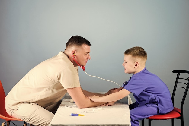 Professional talk medicine and health small boy with dad play Future career nurse laboratory assistant family doctor happy child with father with stethoscope father and son in medical uniform