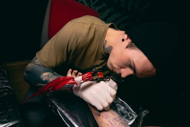 Professional tattoo artist makes a tattoo on the client's arm