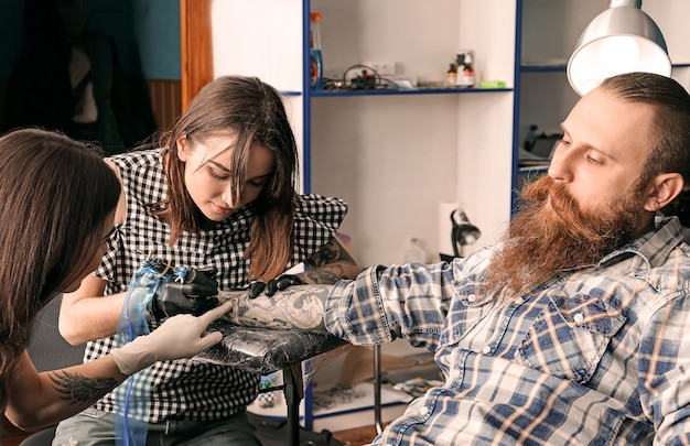 Professional tattoo artist teaching trainee in salon Apprenticeship concept