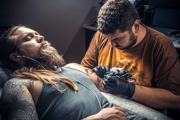 Professional tattooist create tattoo in tattoo parlour./Tattoo specialist makes tattoo in tattoo studio.