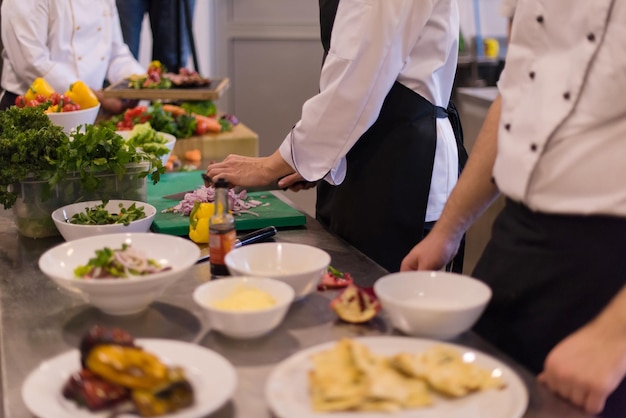 Professional team cooks and chefs preparing meal at busy hotel or restaurant  kitchen