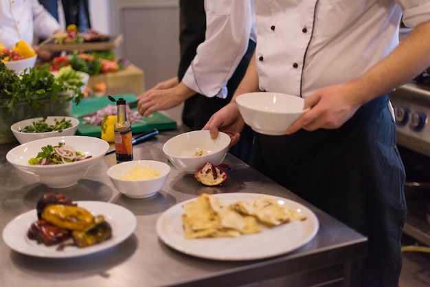 Professional team cooks and chefs preparing meal at busy hotel or restaurant  kitchen