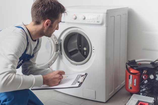 Photo professional technician checking a washing machine he is writing on a clipboard