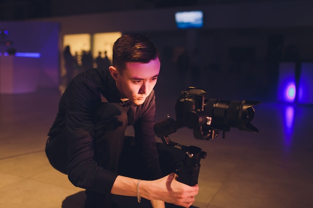 Professional videographer holding camera on 3-axis gimbal. Videographer using steadicam. Pro equipment helps to make high quality video without shaking.