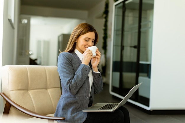 Professional woman enjoying a warm beverage during a break in her modern office space