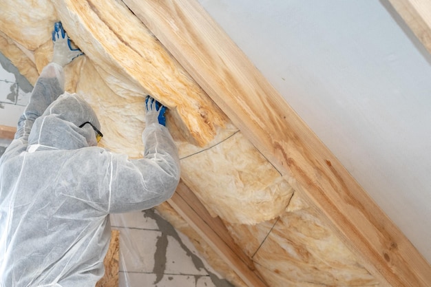 Photo professional workman installing thermal insulation layer under the roof