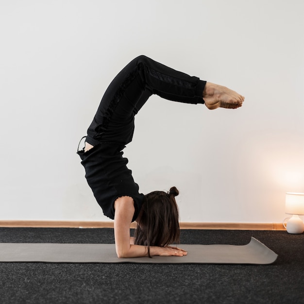 Professional young woman does handstand and keeps balance in a fitness studio. Girl does exercise in yoga pose.