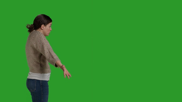 Profile of caucasian woman acting clueless and uncertain, doing i dont know gesture in studio. Young model expressing doubt and acting confused over greenscreen background, unsure person.