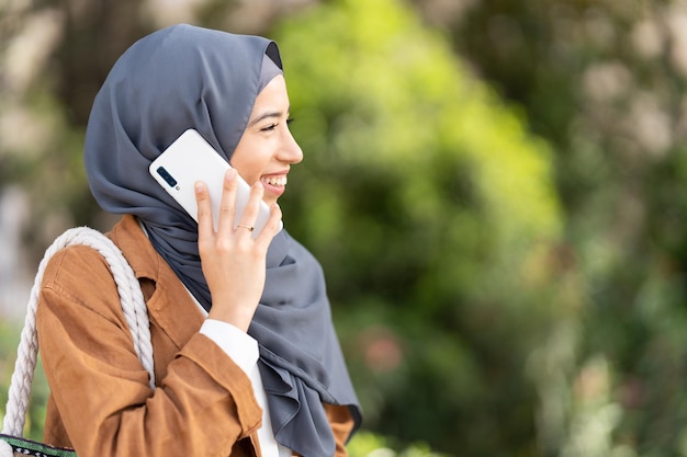 Profile of muslim woman smiling while talking to the mobile