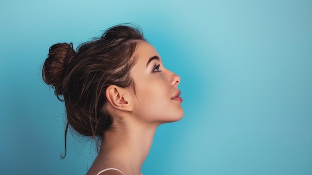 Profile Portrait of Woman with Hair Bun Against Blue Background Beauty Confidence Wellness