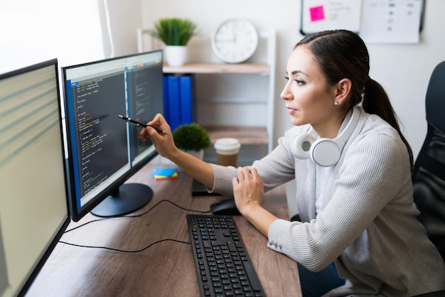 Profile of a professional female programmer checking the coding software of an app on her computer at home