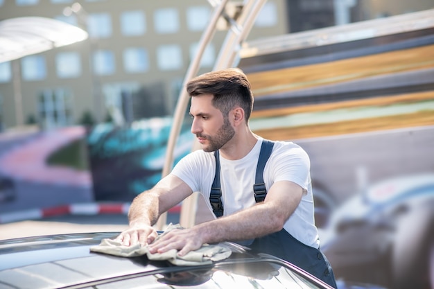 Profile of serious young man wiping car