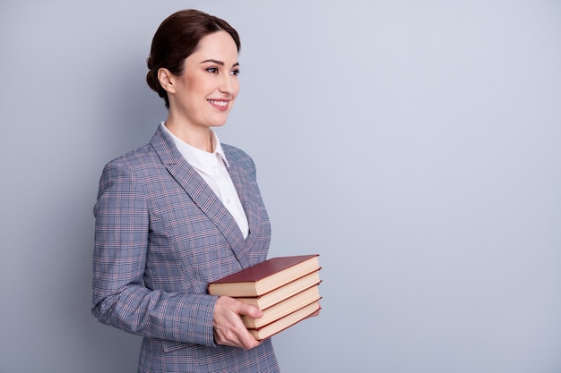 Profile side view portrait of her she attractive qualified intellectual cheerful librarian wearing casual checkered blazer holding book copy empty blank space isolated grey pastel color background