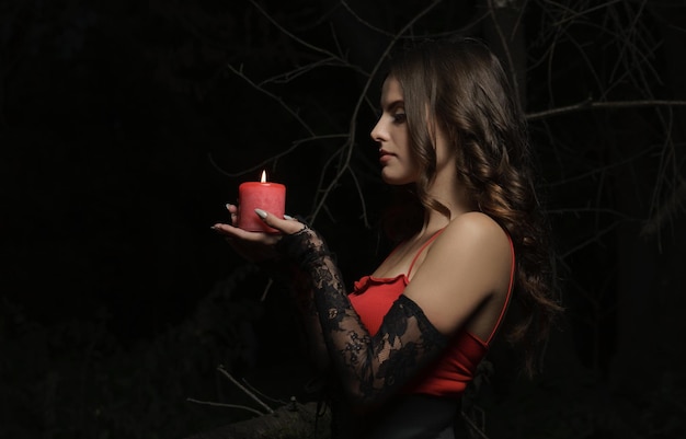 Profile view of a Pretty brunette woman holding candle outdoor at night