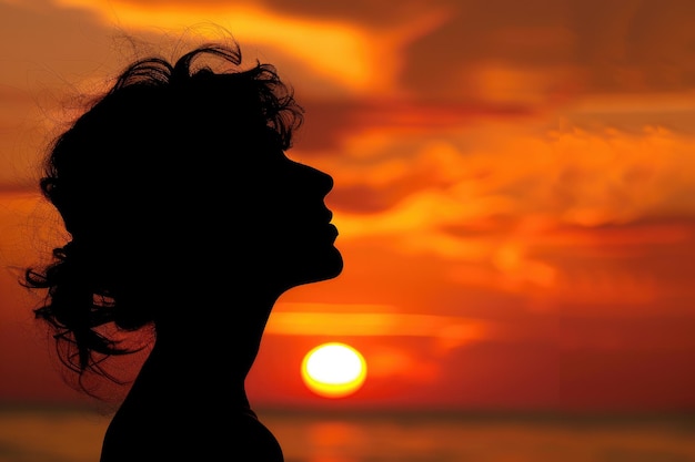 Profile of a woman silhouette watching sun on the beach at sunset