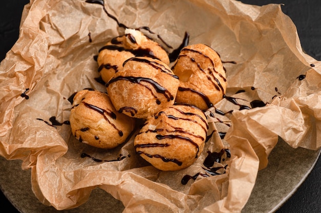 Profiteroles profiteroles with chocolate and topping black background