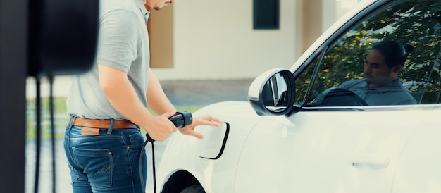 Progressive asian man recharge his EV car at home charging station