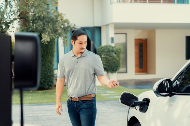 Progressive asian man recharge his EV car at home charging station