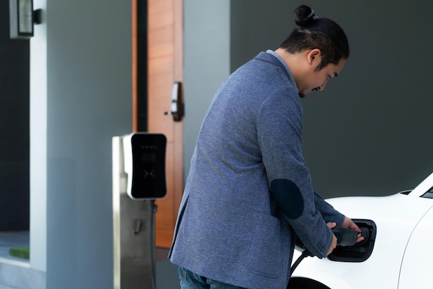 Progressive asian man recharge his EV car at home charging station