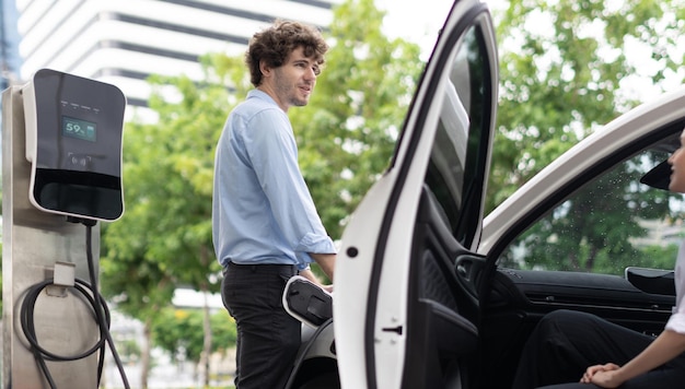 Progressive businessman and businesswoman at charging point and EV car