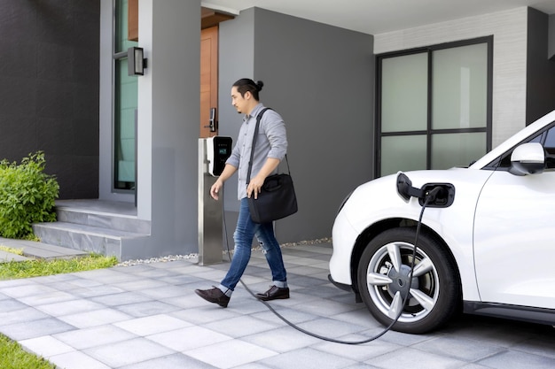 Progressive concept of asian man and electric car with home charging station