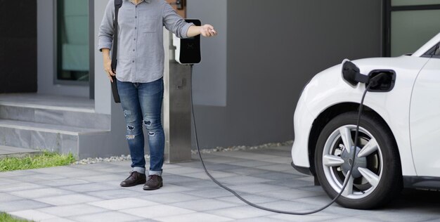 Progressive concept of asian man and electric car with home charging station