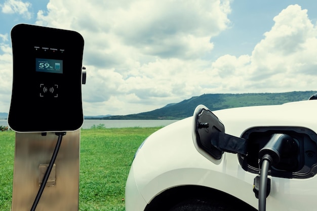 Progressive concept of EV car with green field hill and lake as background