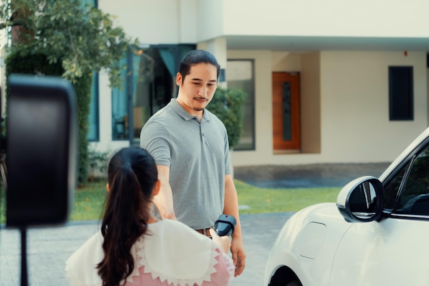 Progressive concept of father and daughter with EV car and home charging station