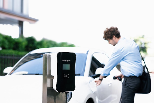 Progressive concept of focus EV car at charging station with blur man background