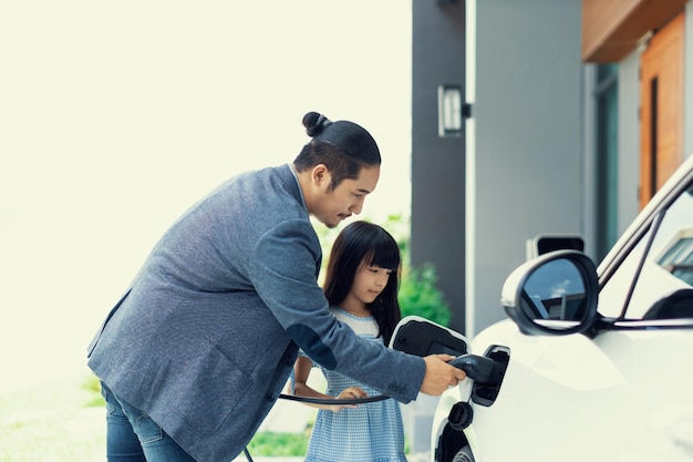 Progressive dad and daughter charging EV car from home charging station