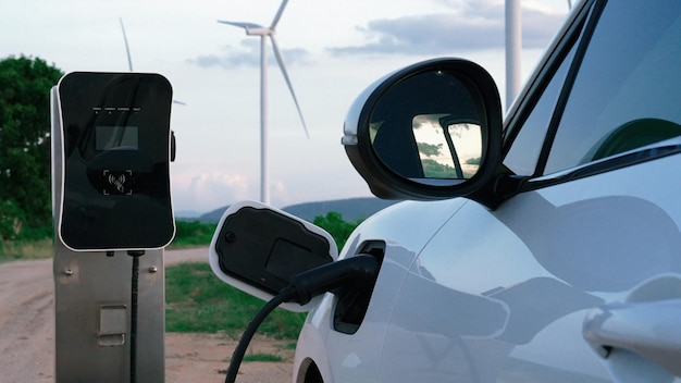 Progressive future energy infrastructure concept of electric vehicle being charged at charging station powered by green and renewable energy from a wind turbine in order to preserve the environment