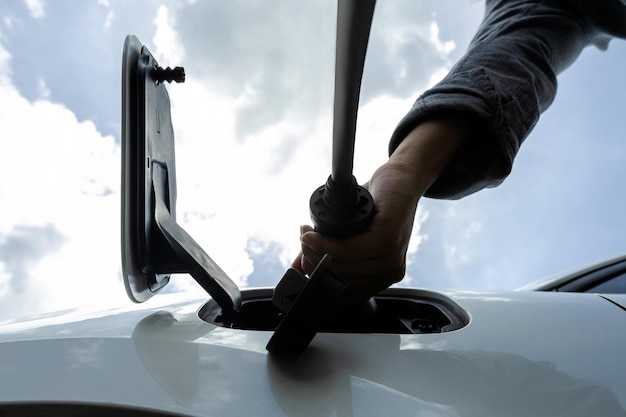 Progressive below view image of hand insert EV charger to socket with cloudscape