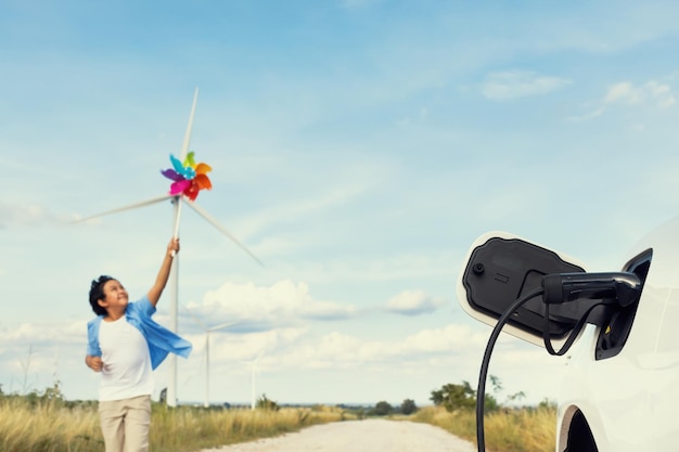 Progressive young asian boy playing with wind pinwheel toy at wind turbine farm