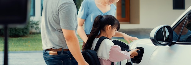 Progressive young parents and daughter living in a home with an electric car