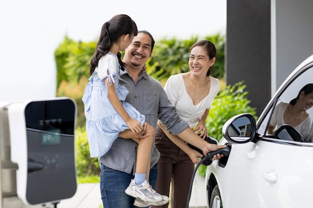 Progressive young parents and daughter living in a home with an electric car