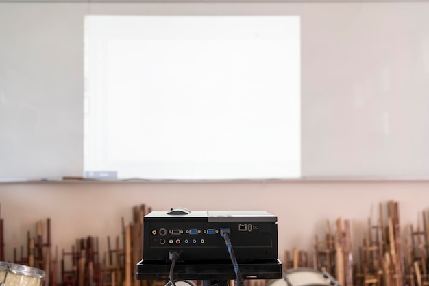 Projector in action with illuminated teacher teaching schoolchildren using projector screen