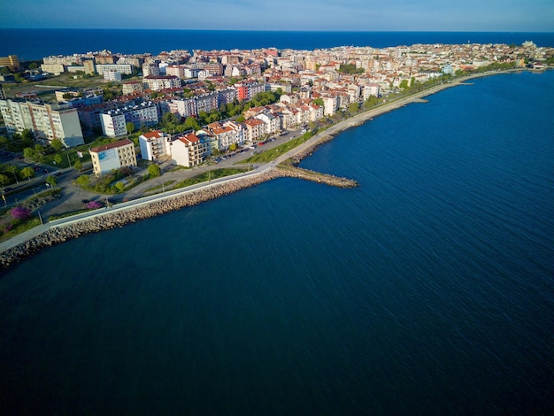 Promenade with people walking near Black Sea against backdrop of town Pomorie in Bulgaria under a cloudy sky