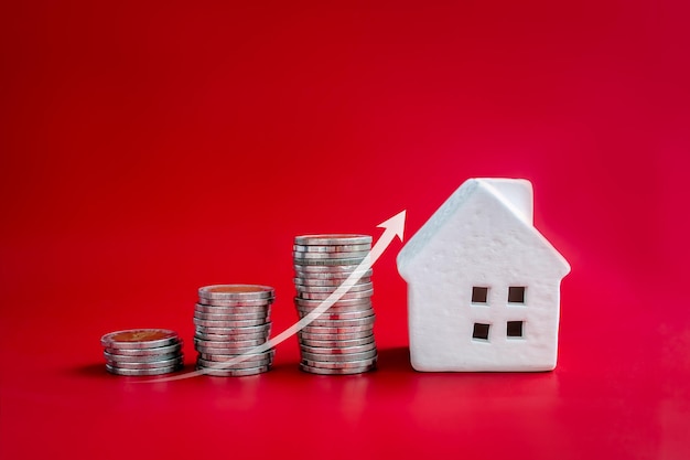 Property value real estate investment home price and inflation concepts Rising up arrow growth on coin stacks as chart steps with minimal wooden house on red background