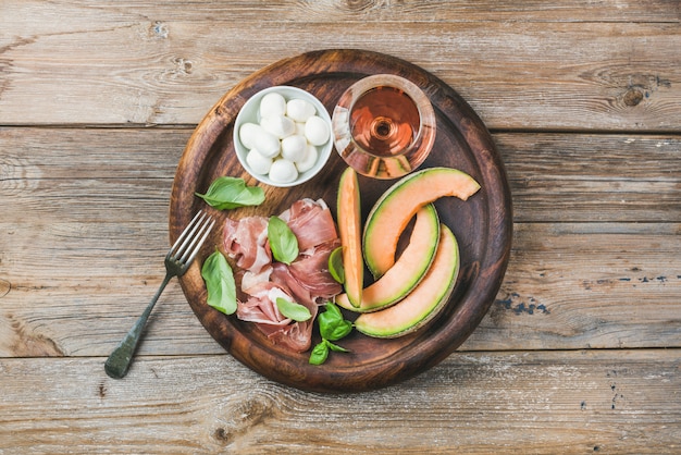 Prosciutto, cantaloupe melon, green basil, mozzarella and glass of wine