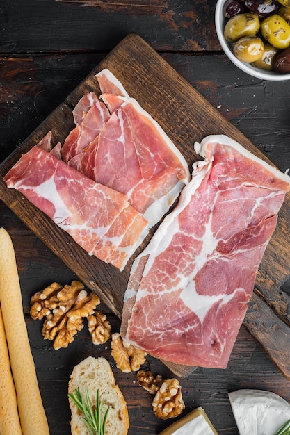 Prosciutto crudo set, on dark wooden background, top view