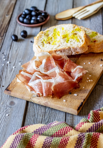 Prosciutto ham and bread on wood