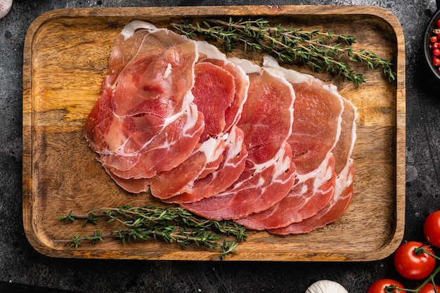 Prosciutto traditional Spanish slices set, on black dark stone table background, top view flat lay