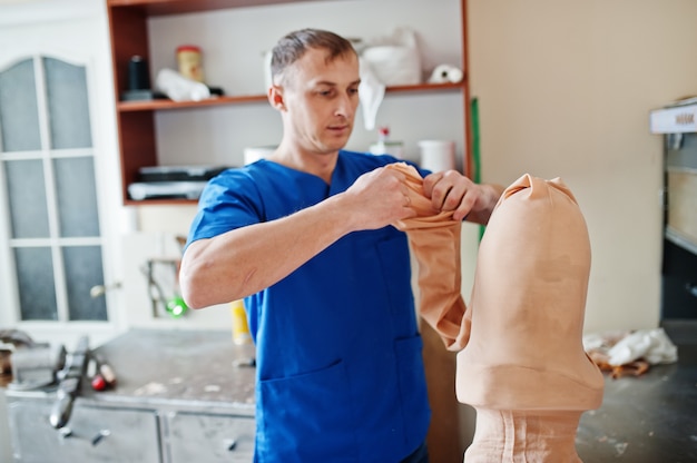 Prosthetist man making prosthetic leg while working in laboratory.