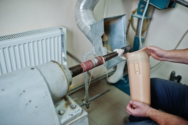 Prosthetist man making prosthetic leg while working in laboratory.